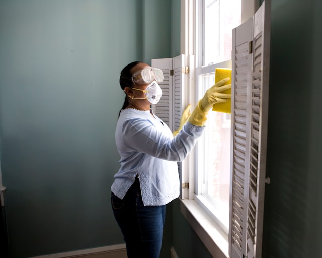 Cleaner tidying a bright modern living room during a home cleaning visit